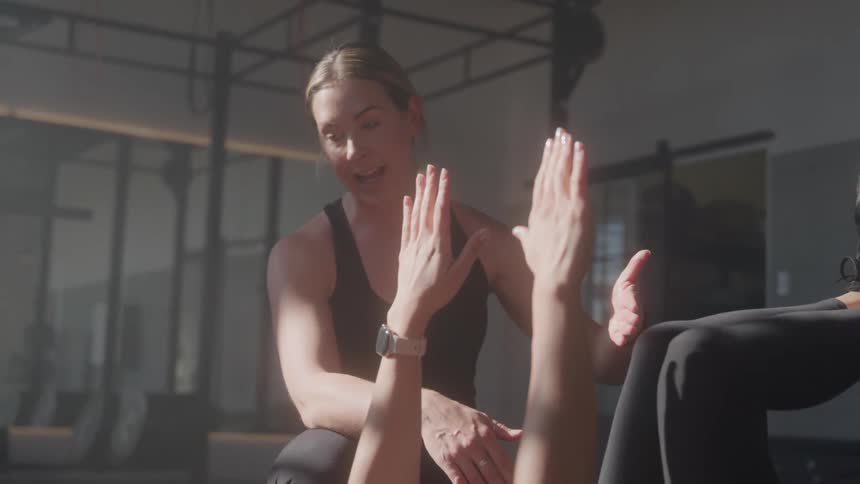 Female yoga instructor correcting clients yoga pose