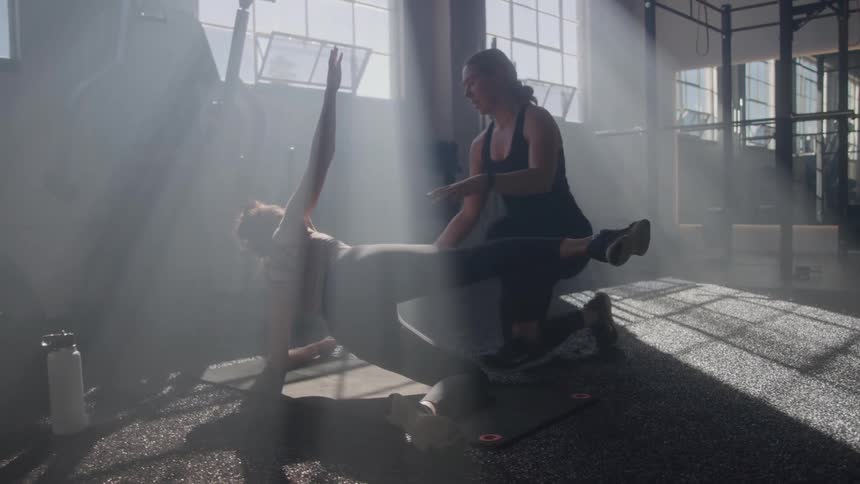 Personal trainer helping a woman do an exercise at a gym