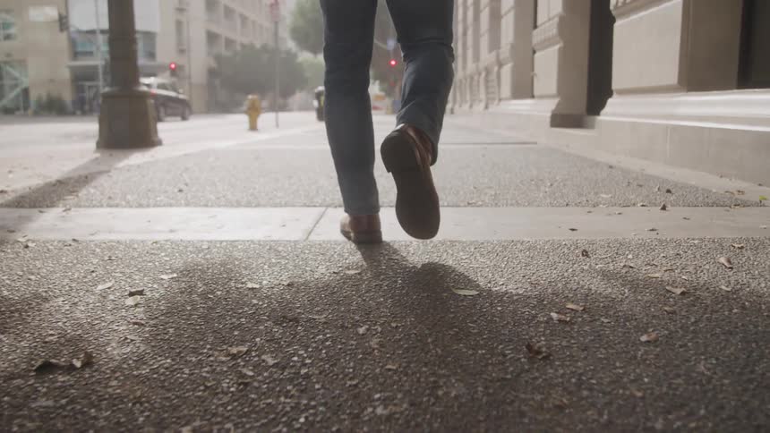 Person in a suit walking on a sidewalk in an urban street