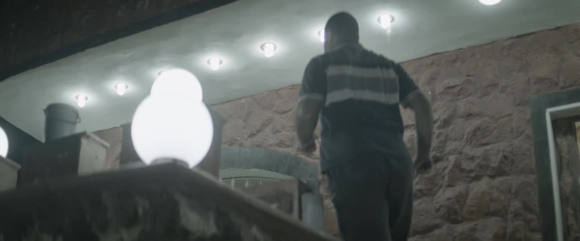 A man carrying a crow bar runs up the stairs at night