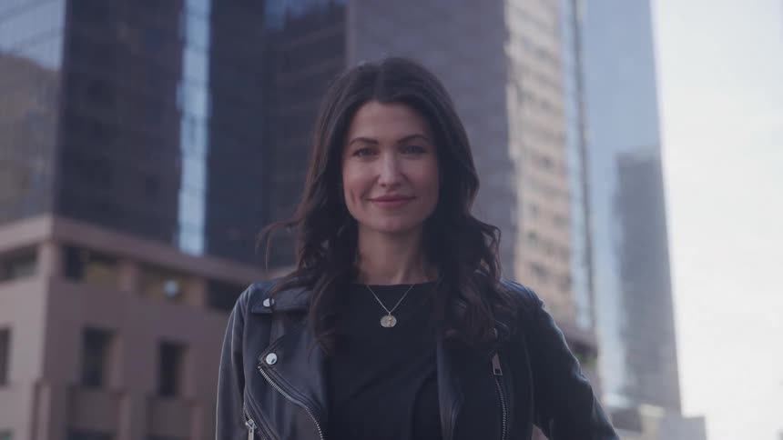 Woman smiles while standing confidently in a city setting