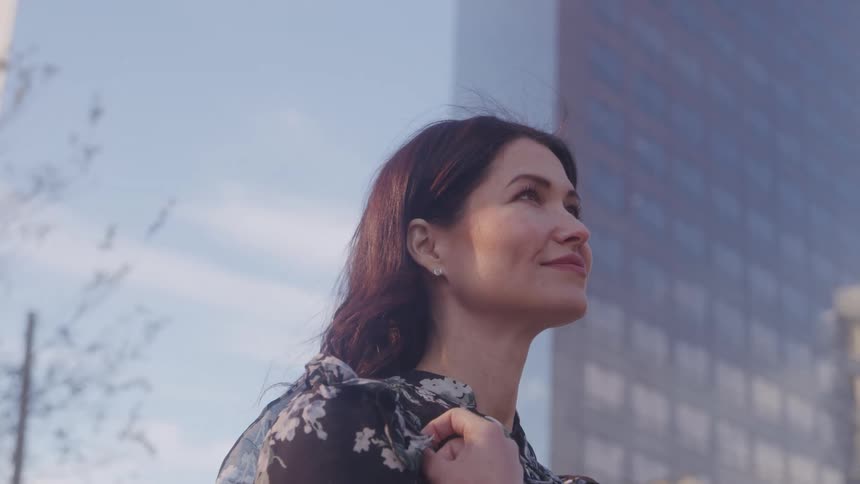 Confident woman smiles looking up in cityscape