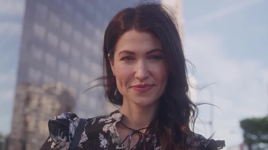 Close up portrait of a young happy woman standing outdoors in a metropolitan city during daytime