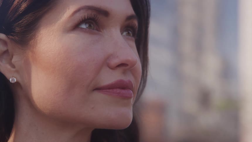 The video shows a closeup side profile of a woman with dark hair and bright eyes looking upwards with a serene expression she is wearing a small sparkling earring a filmsupply watermark is prominently displayed across the center of the frame