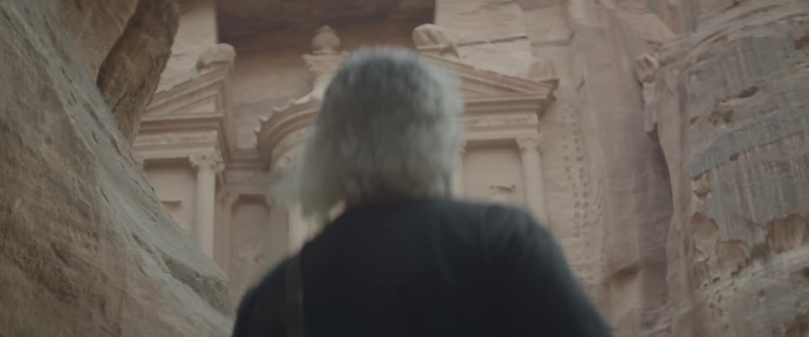 A man approaches a building that is carved into a canyon wall