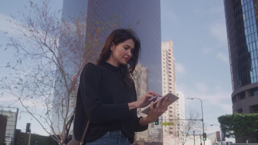 Woman interacting with a tablet in a square in a metropolis