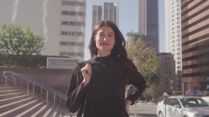 A confident woman smiles on a sunny city street