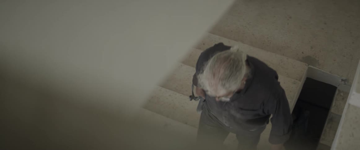 An older man holder a power tool climbs some stairs