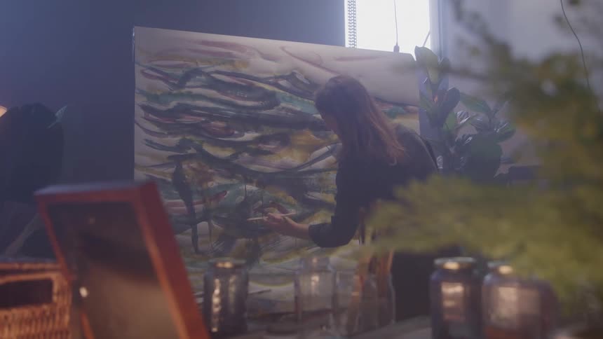 Woman in an indoor space painting a white canvas
