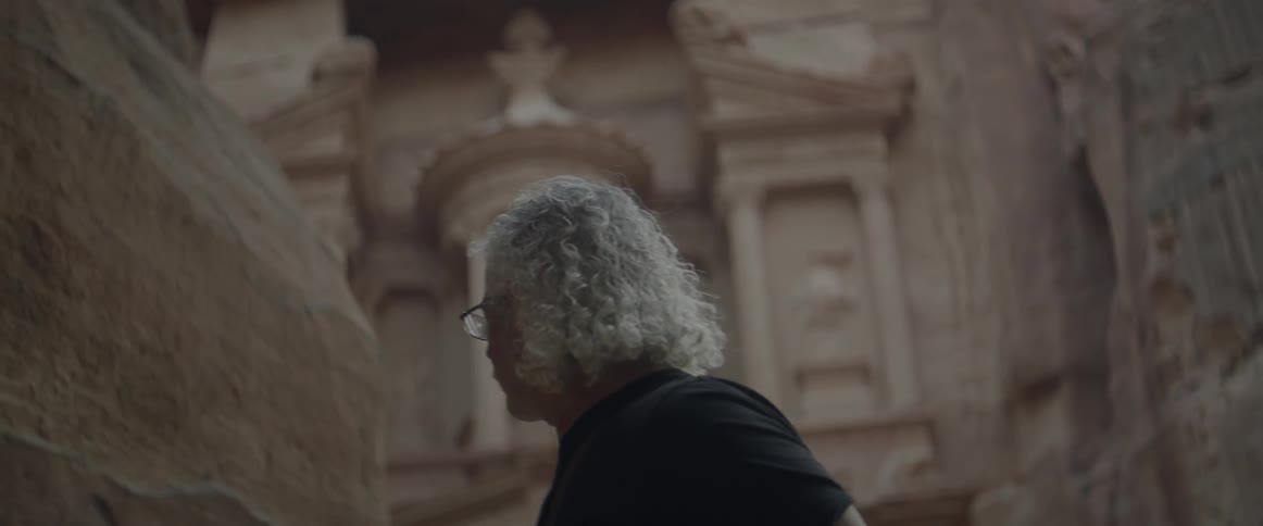 An older man walks away from an ancient edifice