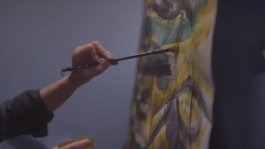 A closeup of a person painting on a canvas