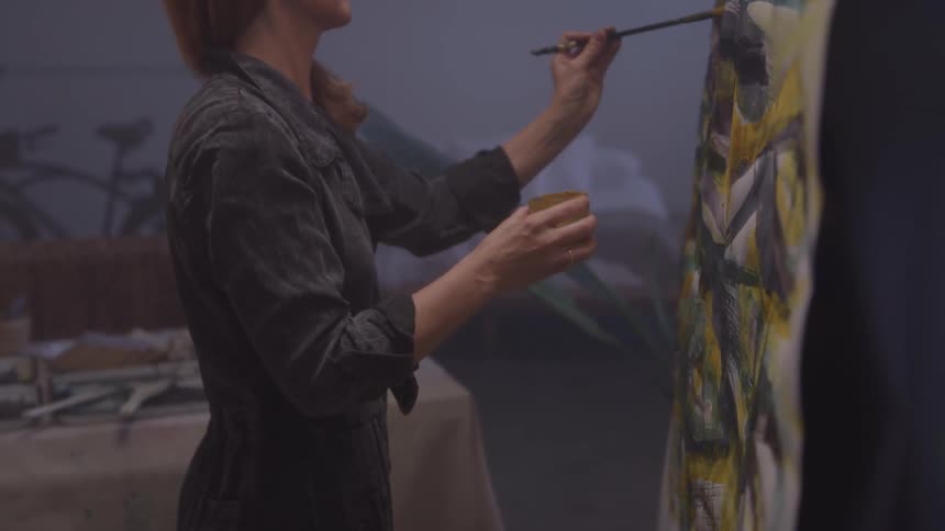 A woman paints on a canvas in the studio