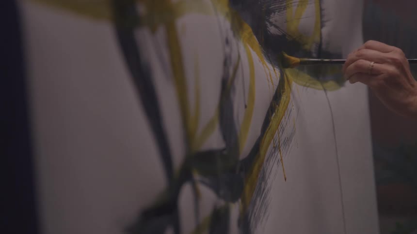 Hand holding a paintbrush and painting a white canvas