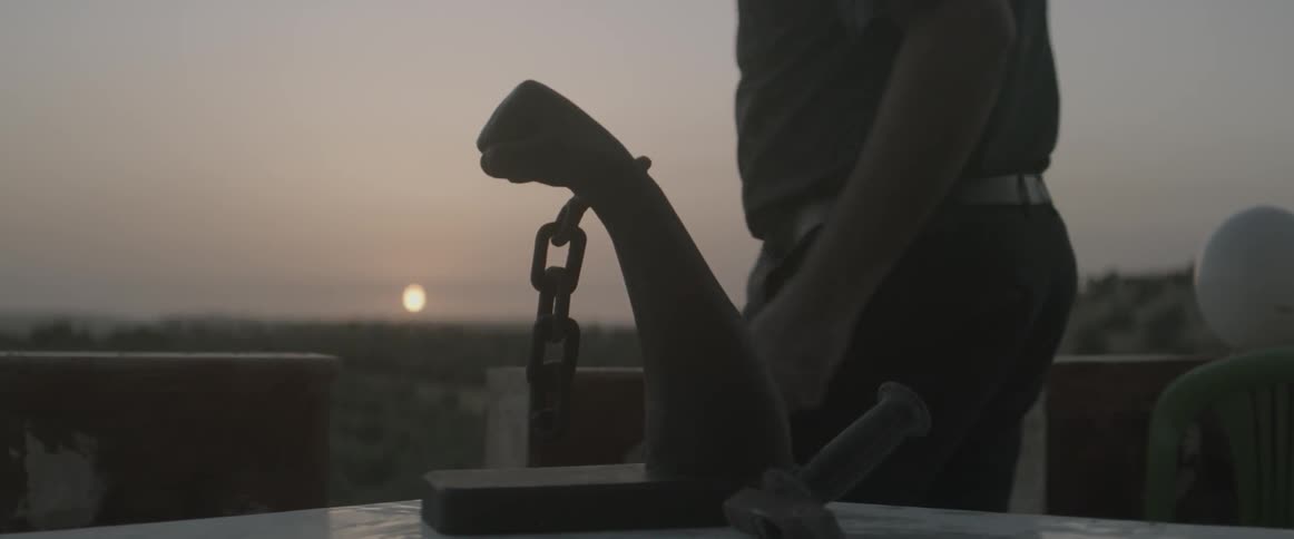 A man walks away from a sculpted fist in chains