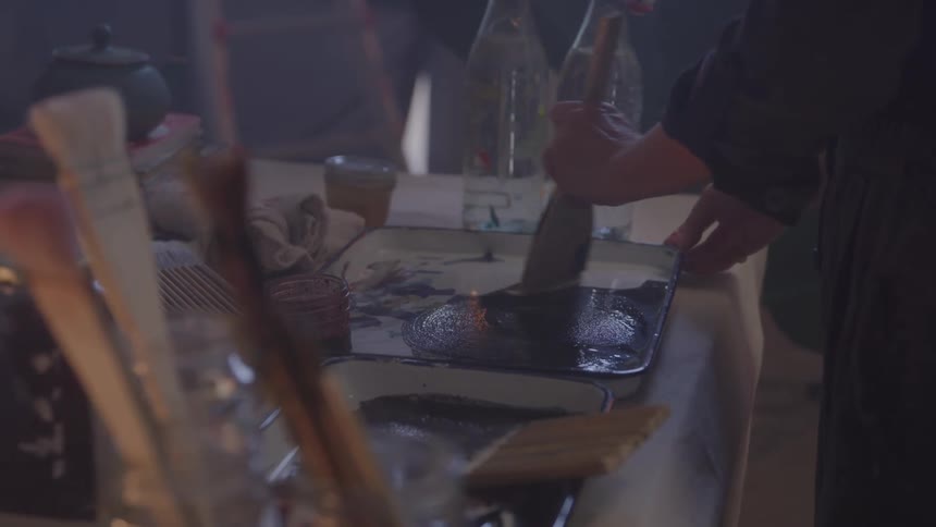 Person mixing paint on a brush