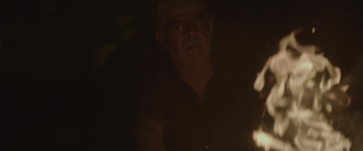 A man looks at the flames of a fire