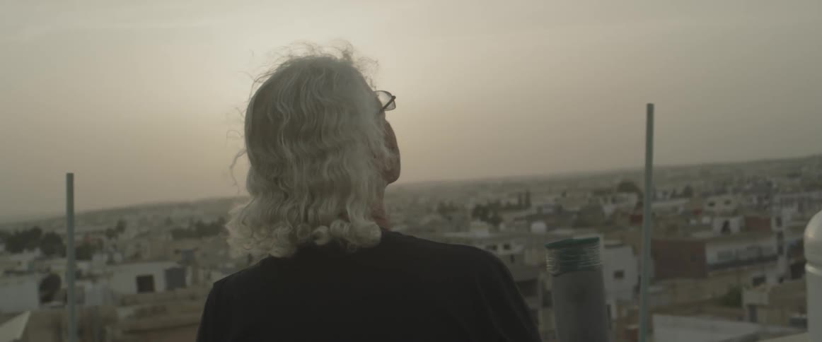 A man looks out over a city on a sunny day