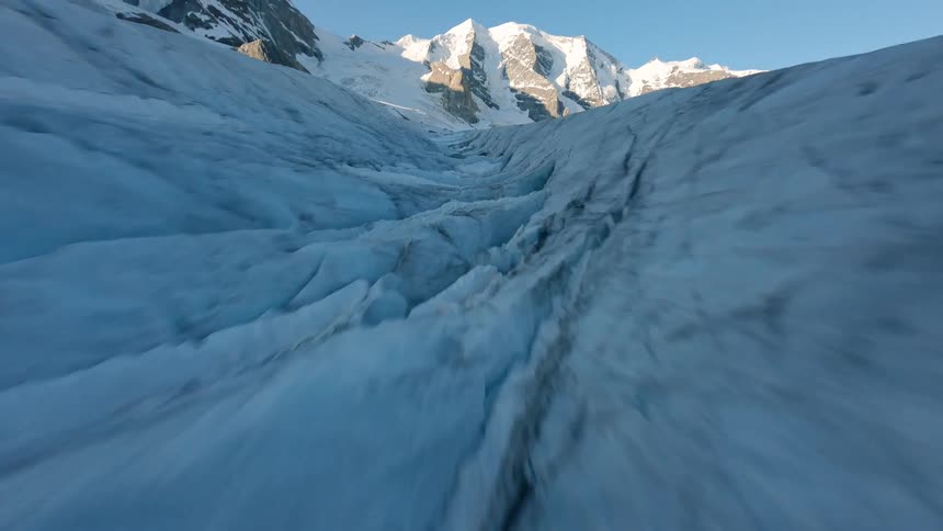 Vast glacier with deep crevasses at the base of snowcovered mountains