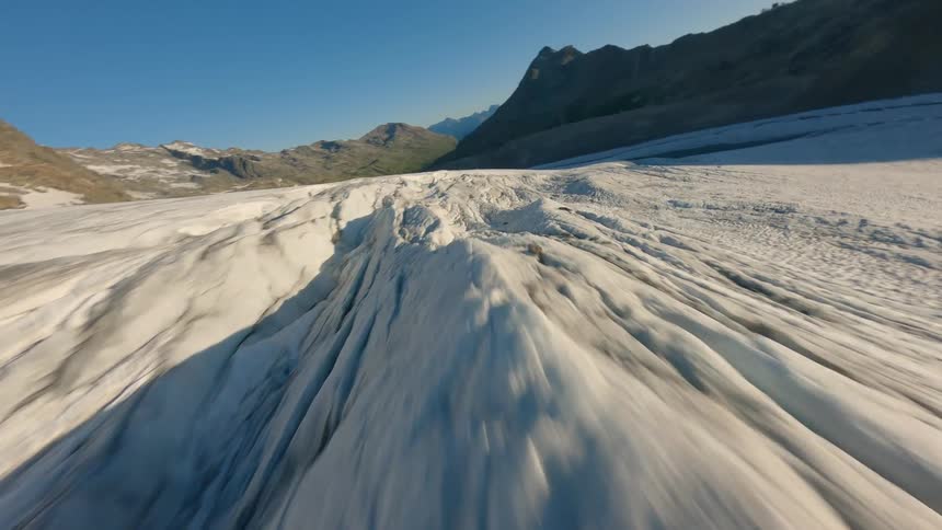 Ice formation sliding between mountains under a clear sky
