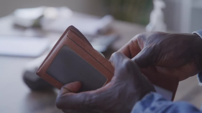 A man hands money from his wallet to a cashier inside a store at midday