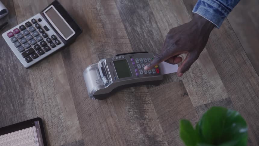 A man inserts a credit card into a pos machine to process a payment for goods inside a store