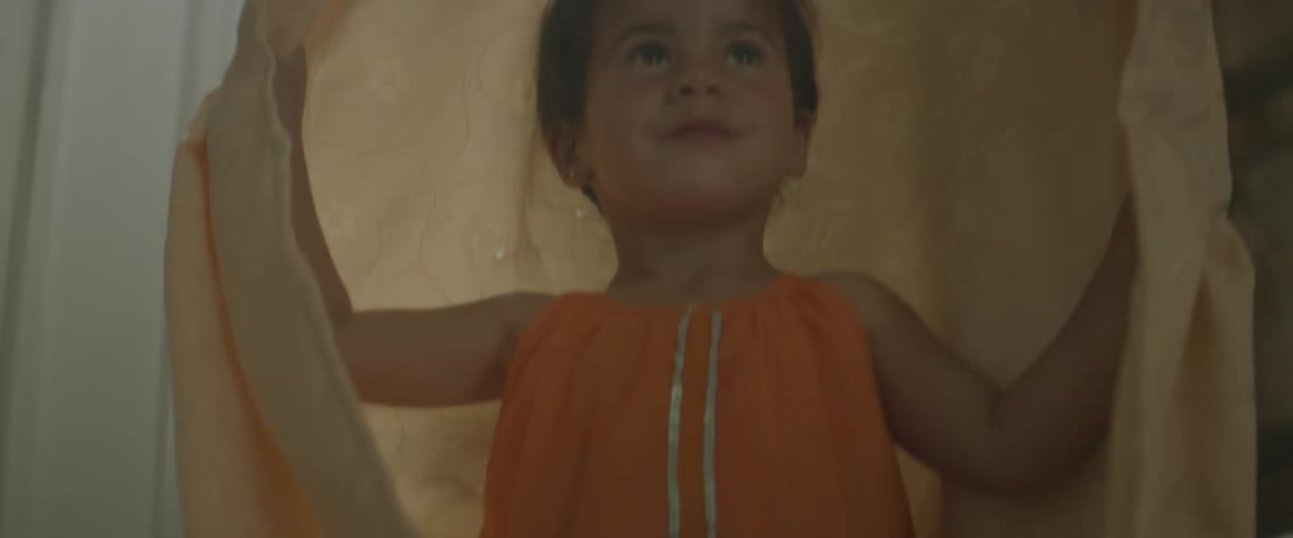 A young girl is wrapped in a blanket and then opens it up