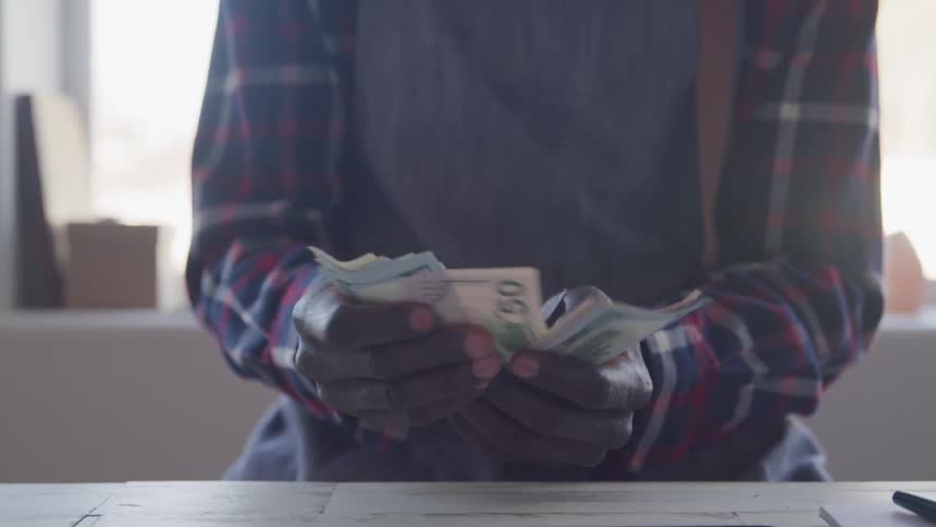 Person counting banknotes with both hands over the table