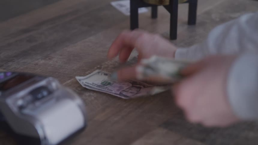 Two hands exchange paper money over a wooden table