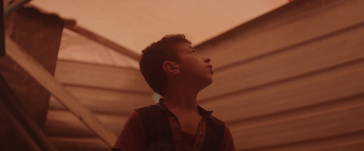 A boy looks around at the sky in wonder