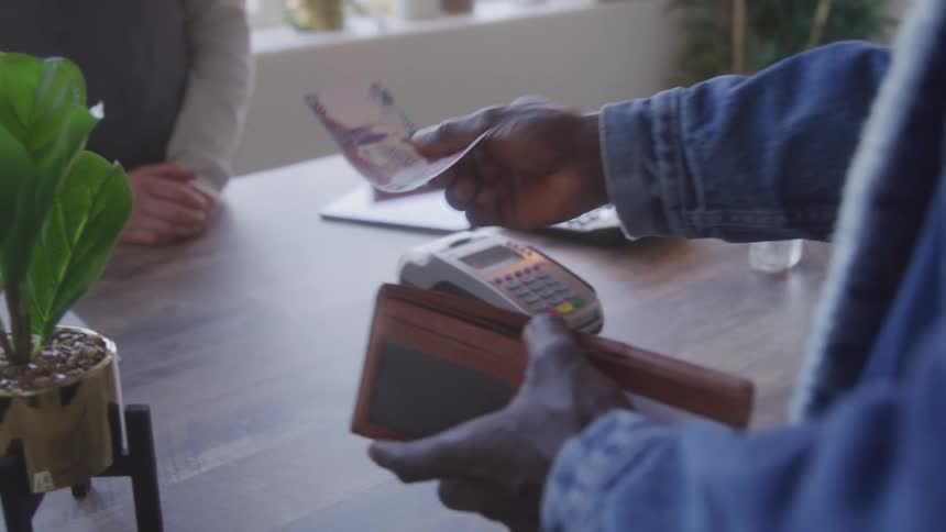A man opening his wallet taking out a banknote and handing it to a woman