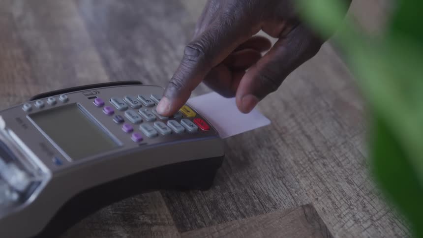 A man inserting a card into a credit card machine and entering his pin to make a payment