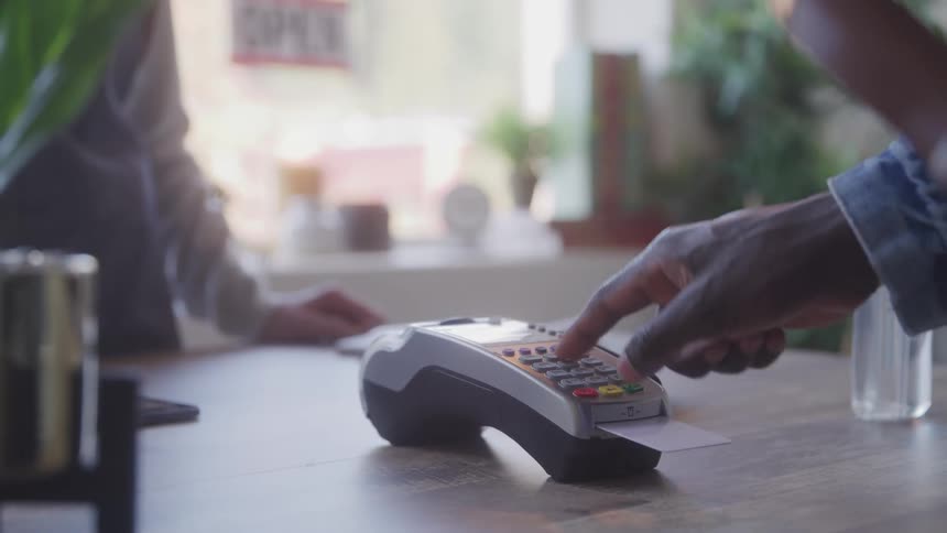 A man inserting a card into a credit card machine entering his pin to make a payment and then removing the card