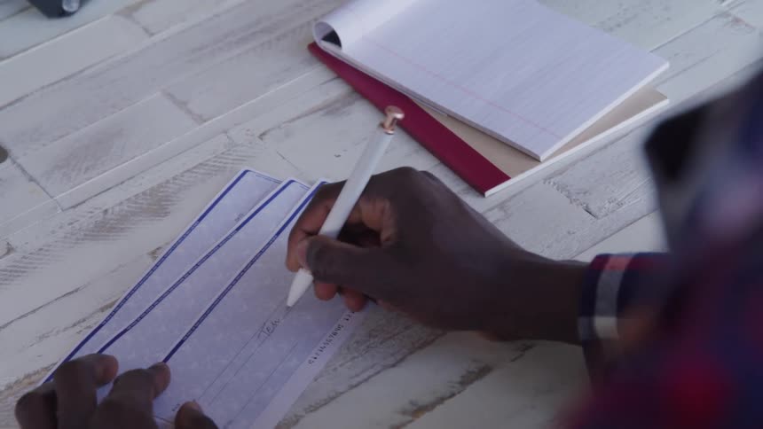 The man is writing on the checks