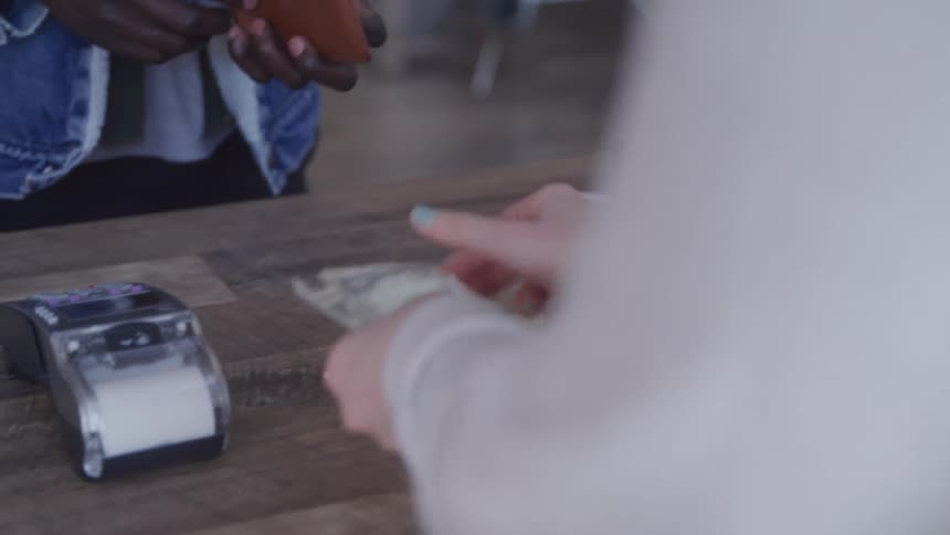Pair of hands of one person handing another a cash payment and receiving change