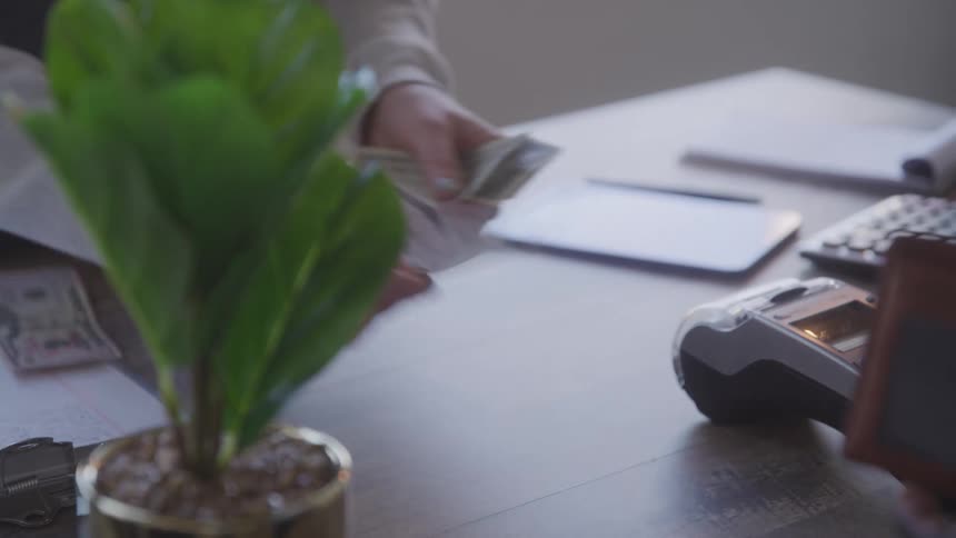 A man hands cash from his wallet to a cashier who then gives him change