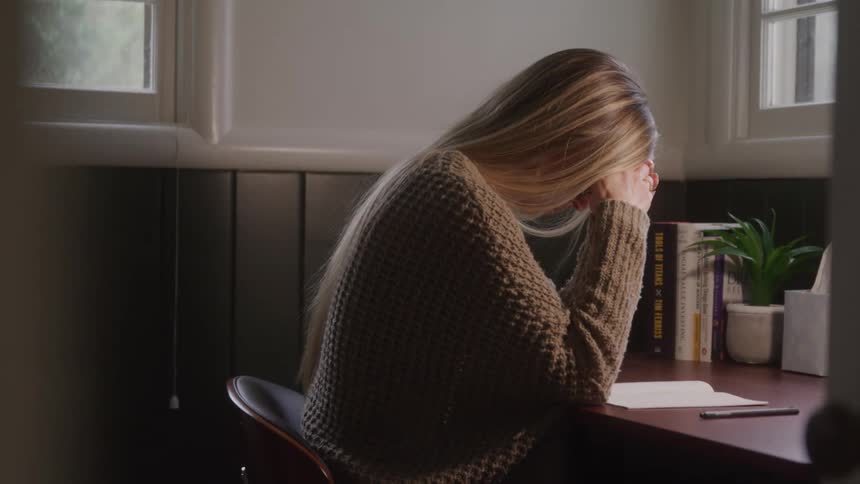 A woman sadly sits at a desk