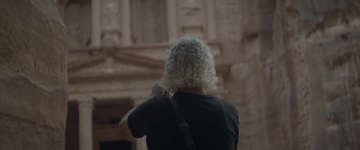 A man takes a photograph of a large stone building