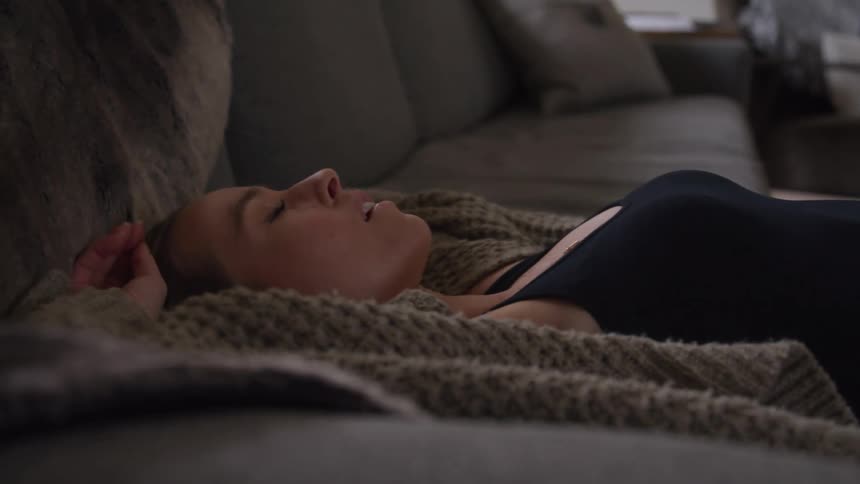 The woman lays down on the couch
