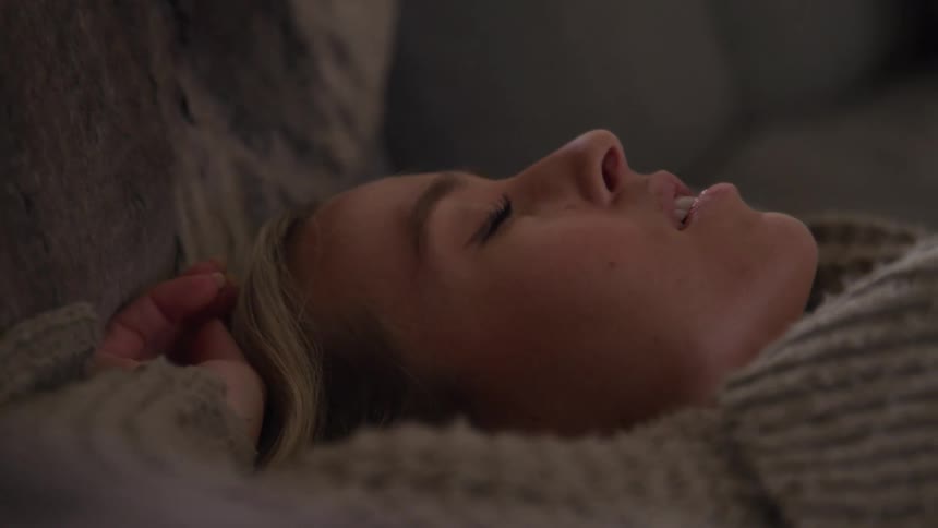Woman falls back onto a couch with her eyes closed
