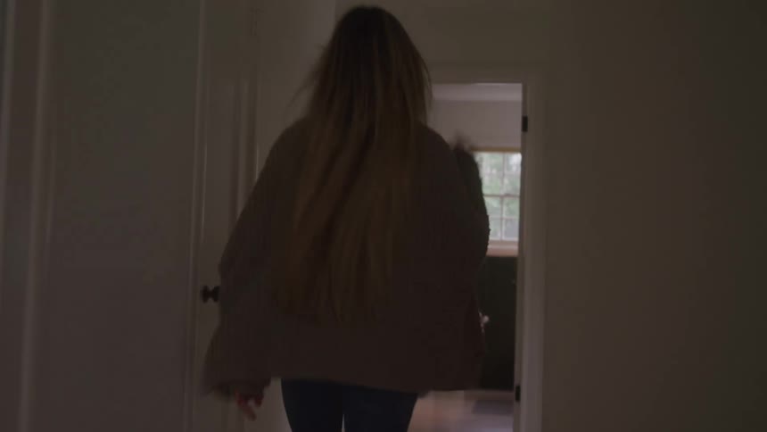 A woman walking around the house complaining and stressed then entering a room and closing the door