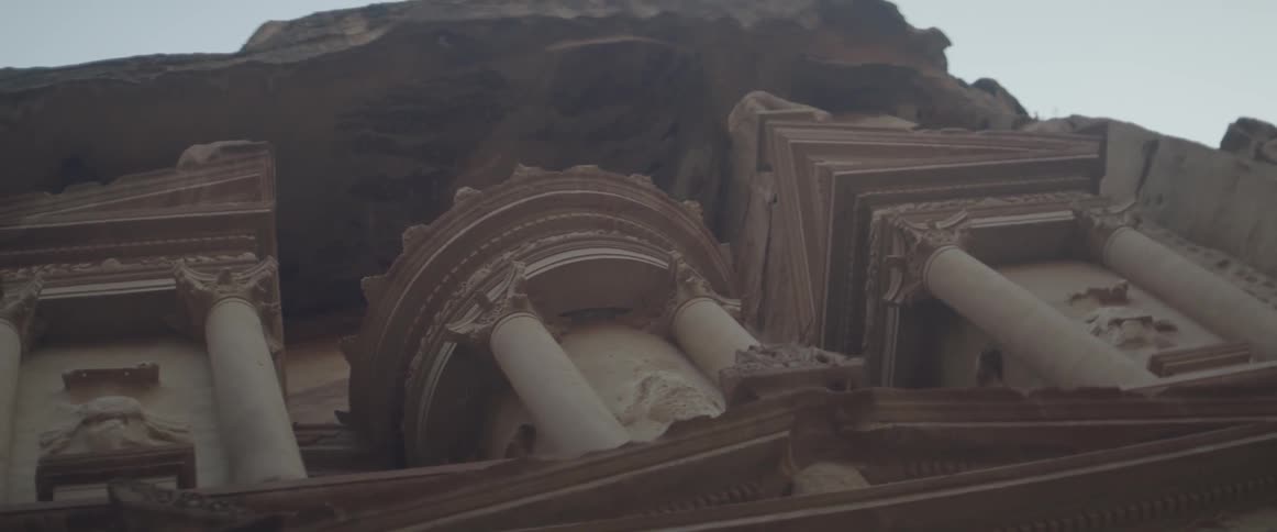A pillared building is carved into a canyon wall