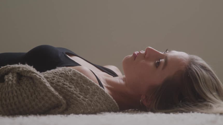 A woman lying on a carpet on the floor with a sad expression