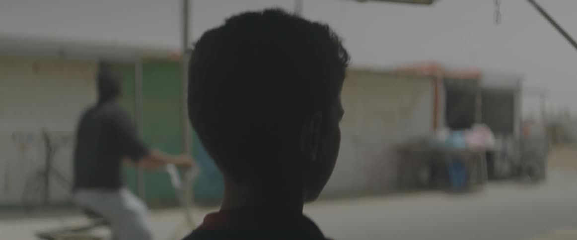 A boy is watching people ride bikes on the street