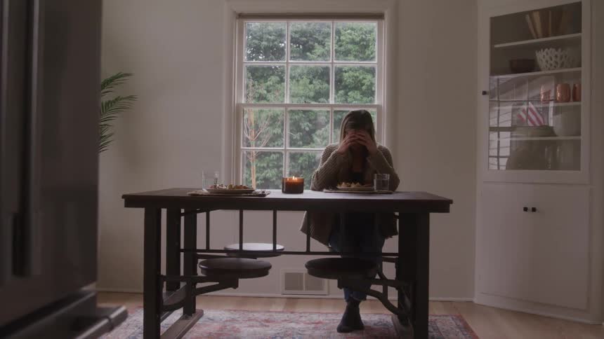 Dejected woman sitting at a served table during the day