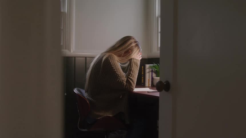Woman sitting at a desk with her hands on her head