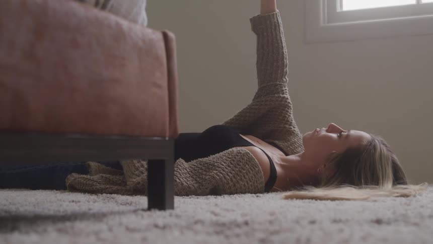 Woman lying on the carpet raises one arm toward