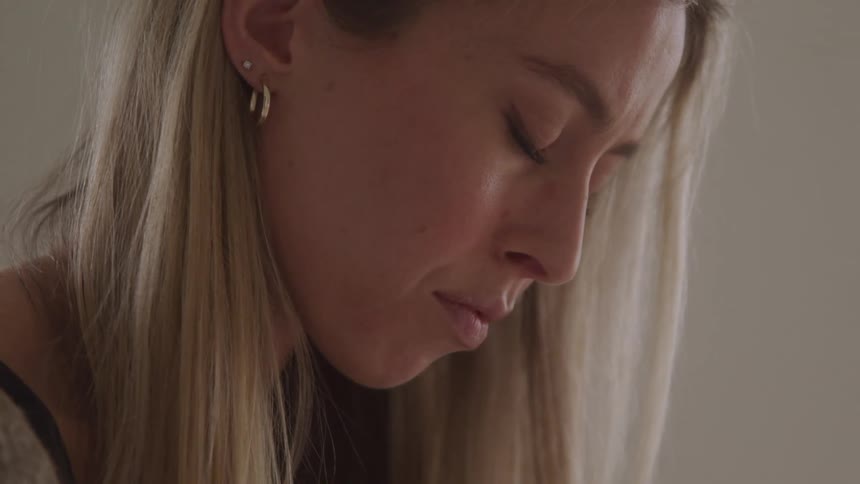 Blonde woman in an indoor space closing her eyes