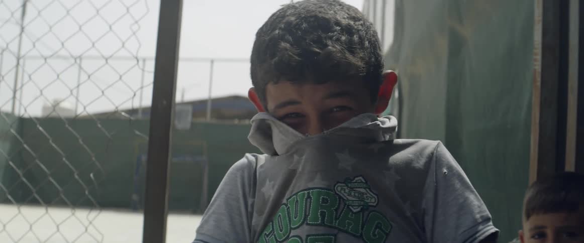 A boy covers his lower face with a shirt and then laughs