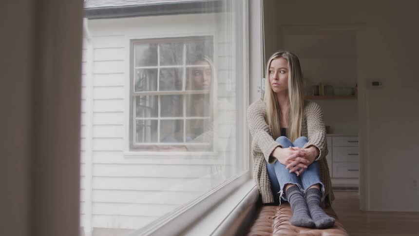 A woman sadly looks out the window