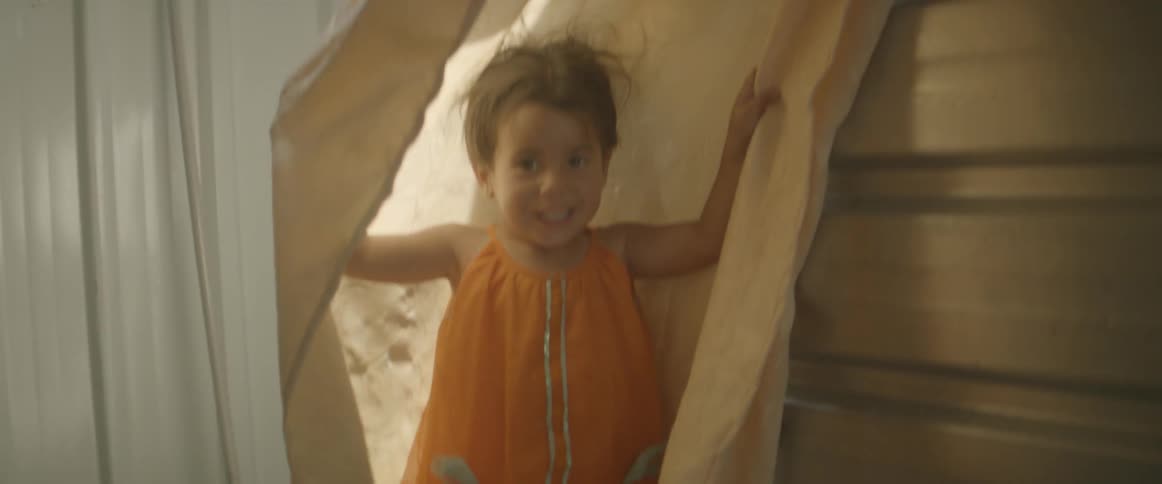 Young girls smiling as she reveals herself from behind a curtain